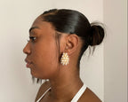 Woman wearing pearl tear gold 18k gold earrings with a neutral background
