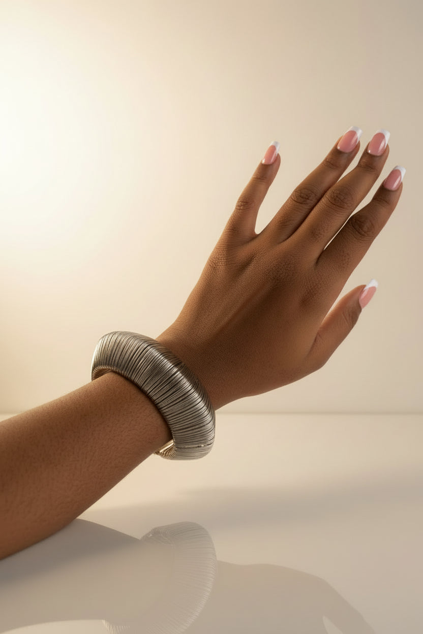 Hand wearing a silver bracelet with a plain background