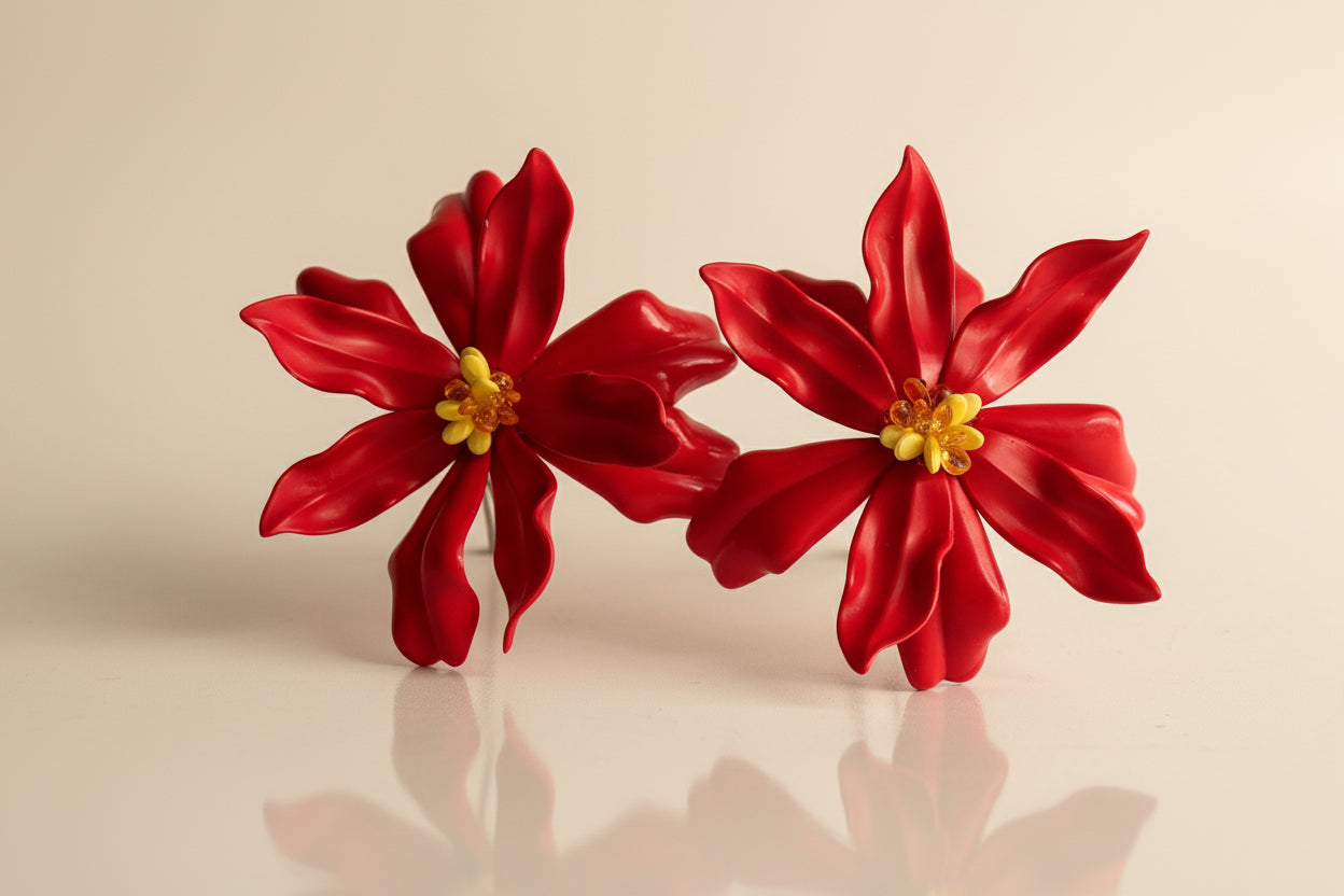 Red flower-shaped earrings with yellow centers on a white background