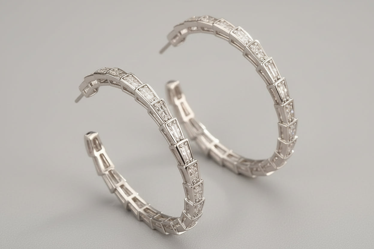 Gold hoop earrings with intricate design on a beige fabric background